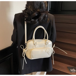 Detail showing bow stitching and long side drawstrings on a cream faux leather boston bag