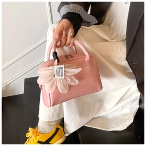 Detailed shot of pink pebble leather Boston bag with a mesh flower charm on the handle