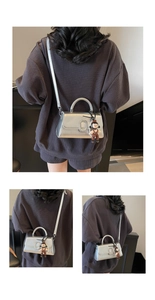 Detail view of silver metallic textured crossbody bag with top handle and cute charm