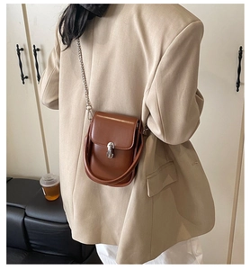 Detailed back view of a caramel leather crossbody bag with silver chain strap and metal clasp