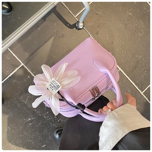 Detailed close-up of a lilac Boston bag with lychee texture and white floral pendant