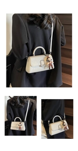 Detail of cream white leather handbag with silver buckle and cute cartoon figure pendant