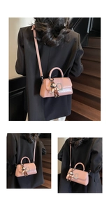 Detail view of pink crossbody bag featuring silver metal buckle and pearl charm accessories