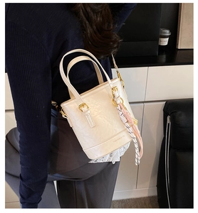 Detail of a creamy white bucket bag with gold hardware and brand logo on the bottom