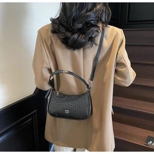 Close-up of black woven leather handbag with silver logo on office style model