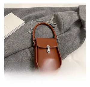 Detailed shot of brown leather mini handbag with silver metal chain and rotary lock