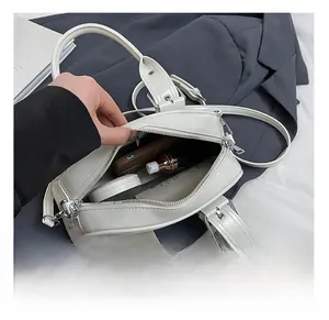 Spacious interior of white leather Boston bag showing phone, lipstick, and cosmetics