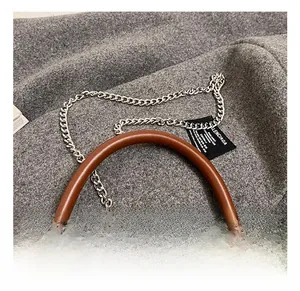 Detail of the brown leather handle and silver metal chain strap of the crossbody bag