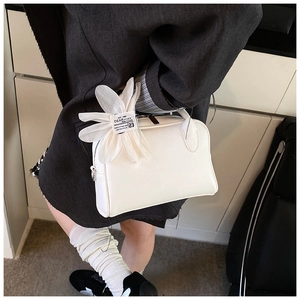 Detailed macro view of white Boston bag with litchi grain and decorative flower charm