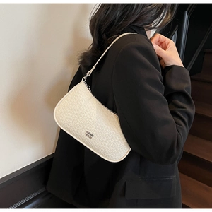 Close-up of cream underarm bag showing embossed faux leather texture and metallic logo