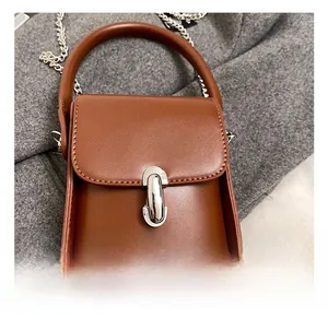 Close-up of a brown leather mini bag featuring a silver metal lock and chain strap