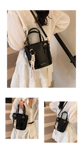 Detail view of black leather bucket bag with gold hardware and elegant silk scarf accessory