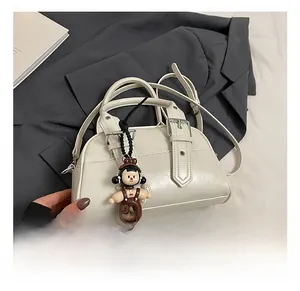 Detail of white leather Boston bag featuring silver buckles and cute character charm