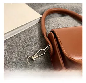 Detailed close-up of brown leather bag showing silver metal chain hooks and stitching