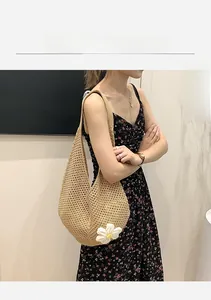 Detail of a khaki hand-woven crochet tote bag featuring a white knitted daisy flower