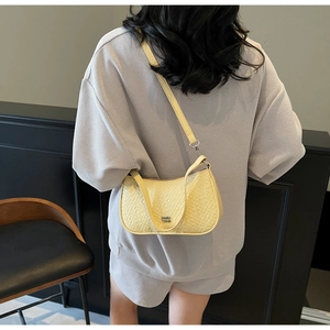 Close-up of pale yellow underarm bag with crocodile pattern and adjustable strap