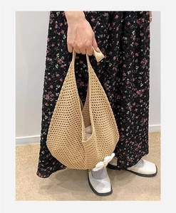 Detail view of beige hollow knit tote bag with a white daisy floral charm accessory