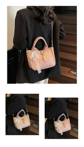 Pink lychee texture bucket bag with pearl bow charm shown on model in outdoor setting