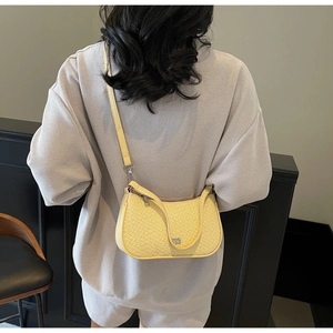 Detailed view of ginger yellow half-moon bag featuring woven texture and adjustable strap
