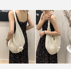 Detailed view of a white woven shoulder bag featuring a cute 3D daisy flower pendant