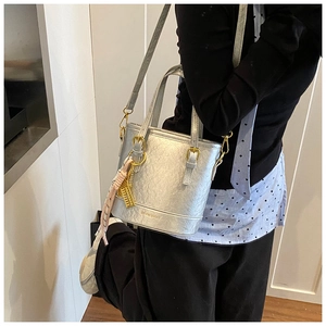 Detail showing the silver bucket bag with gold Eiffel Tower pendant and shoulder strap