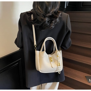 Vista lifestyle di una borsa a secchiello in pelle bianca con chiusura dorata su modella