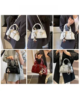 Detail view of retro Boston handbag showing leather buckle straps and plush charm decor
