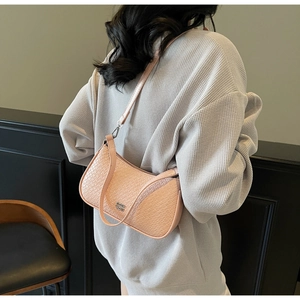 Pink woven underarm bag with zipper closure and metallic logo on model's shoulder