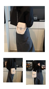 Detail of a minimalist cream PU leather crossbody bag with silver hardware and U-handle