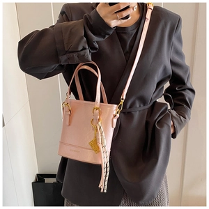 Detail view of pink bucket bag with gold accents and fashionable braided pendant