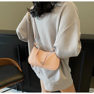 Detail view of pink embossed crocodile texture shoulder bag with silver metal logo on model