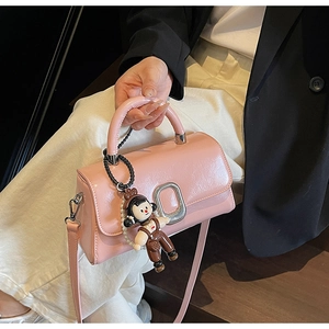 Pink leather handbag detail featuring silver oval clasp and cute cartoon doll pendant accessory