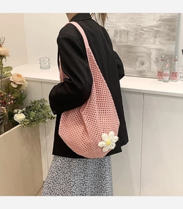 Pink knit shoulder bag detail with hollow mesh texture and white crochet flower charm