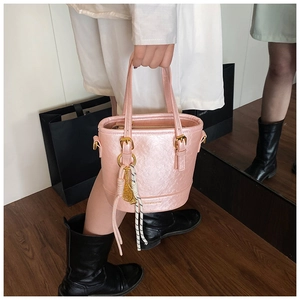 Detail view of pink bucket bag with crackle leather texture and golden metal buckle