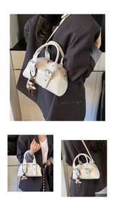 Close-up of cream Boston bag with metallic buckle detail and cute boy doll charm