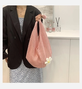 Detailed shot of pink crochet tote bag featuring white daisy charm and mesh texture