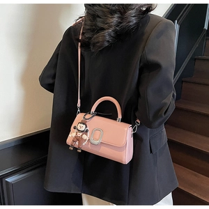 Detail view of pink patent leather handbag with silver clasp and cute cartoon charm