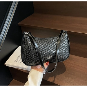 Close-up of black woven texture shoulder bag with metallic logo and sleek zipper detail