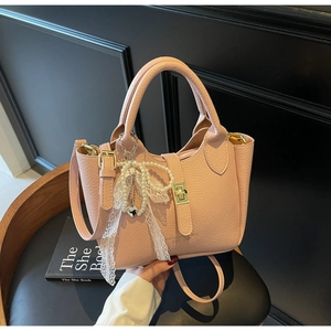 Pink lychee texture handbag with gold lock, pearl charms, and lace bow detail