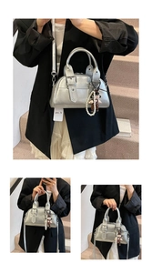 Detail of silver metallic Boston bag featuring a doll charm and detachable shoulder strap