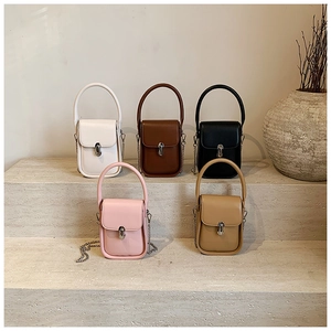 Detailed view of mini crossbody bags in five colors on a textured stone display