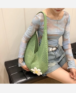 Close-up of green crochet tote bag featuring a large handmade white daisy flower detail