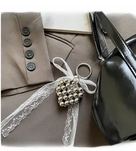 Pendentif perlé en cœur avec ruban en dentelle blanche sur sac à main de luxe