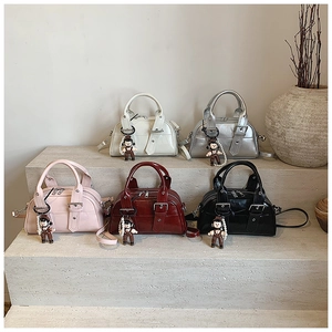 Detailed display of five colorful glossy Boston bags with decorative charms on stairs