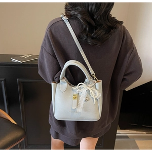 Detail view of light blue lychee pattern bucket bag with golden lock and lace bow charm