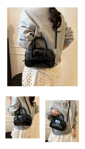 Détail du sac Boston en cuir verni noir avec nœud décoratif et double poignée