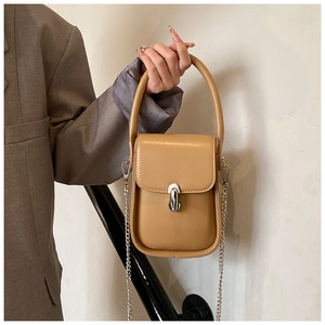 Detail of light brown leather crossbody bag with silver clasp and chain strap