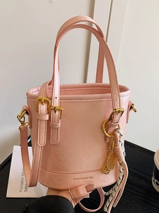Minimalist pink leather bucket bag with gold hardware and a small tennis racket charm