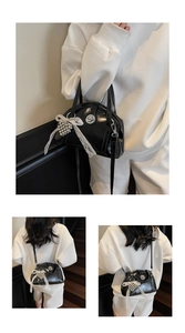 Détail du sac brillant noir avec nœud en dentelle blanche et pendentif coeur en métal