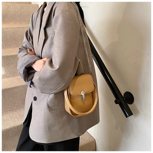 Detail view of khaki mini crossbody bag with silver chain and U-shaped leather handle